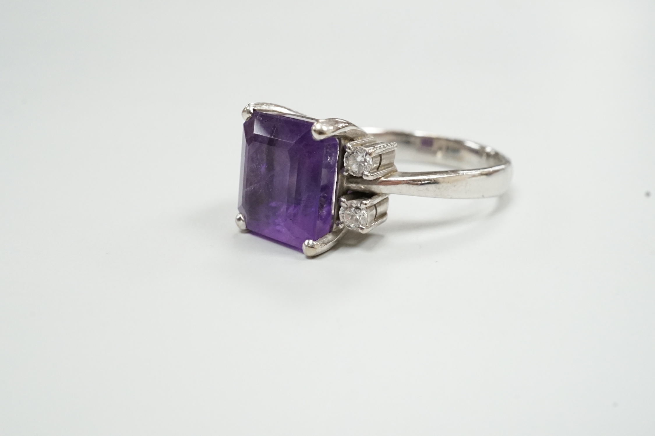 A modern 585 white metal single stone amethyst and four stone diamond set dress ring, size S/T, gross weight 8.1 grams.
